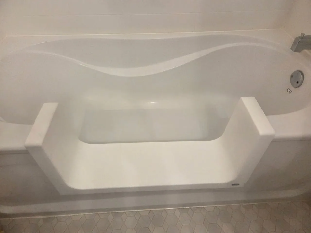 A step-through cut-out lowered into the wall of an existing bathtub