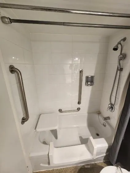 A walk-in tub-to-shower conversion with grab bars and a seat in Napanee